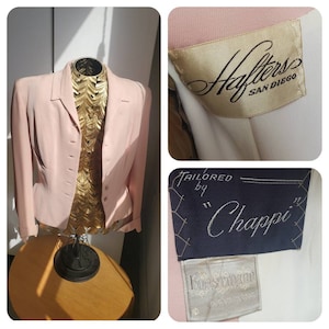 May include: A pale pink blazer with a traditional button-down style. The blazer is displayed on a gold mannequin. The labels inside the blazer read "Hafters San Diego" and "Tailored by Chappi".