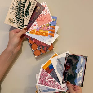 Puede incluir: Una colección de postales rectangulares con diversas ilustraciones gráficas de lugares como Melbourne, Miami y Austria. Las tarjetas muestran colores vibrantes, estilos artísticos variados y texto impreso como G'day from Melbourne, Albert Park, Miami y See Austria This Summer.