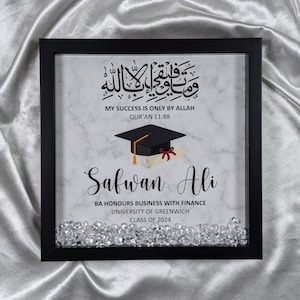 May include: A square black shadow box frame containing a white marble-patterned background with Arabic calligraphy, the text "MY SUCCESS IS ONLY BY ALLAH QUR'AN 11:88", a graduation cap, a diploma, the name "Safwan Ali", and academic details.