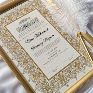 May include: A framed marriage certificate with gold and floral border details. The certificate features the names Elias Mohamed and Shanaz Begum, along with the date August 19, 2015. A white feather quill rests on the frame.