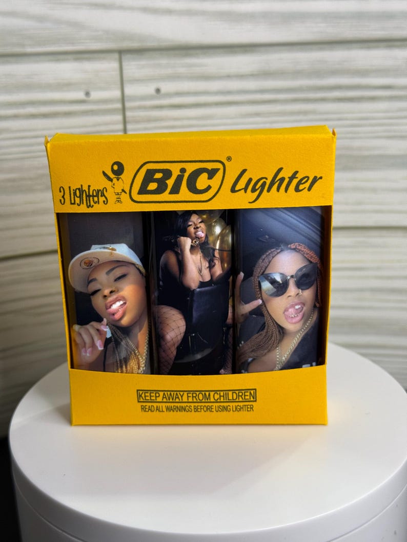 May include: A yellow box of three BIC lighters. Each lighter features a different image of a woman. The box has the BIC logo and the text "3 Lighters". The bottom of the box has a warning.