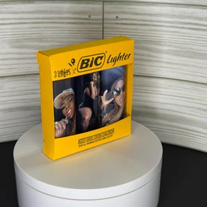 May include: A yellow box of BIC lighters featuring a photo of three women. The box reads "3 Lighters" and "BIC Lighter" in black text. The box also has the warning "KEEP AWAY FROM CHILDREN READ ALL WARNINGS BEFORE LIGHTING LIGHTER."