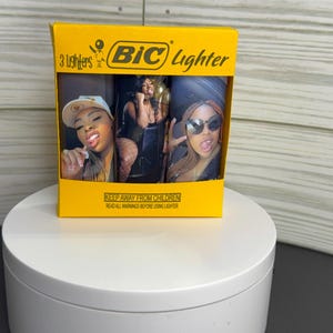 May include: A yellow BIC lighter package containing three lighters. Each lighter features a different image of a woman. The package has the BIC logo and the text "3 Lighters". The bottom of the package has the text "KEEP AWAY FROM CHILDREN".