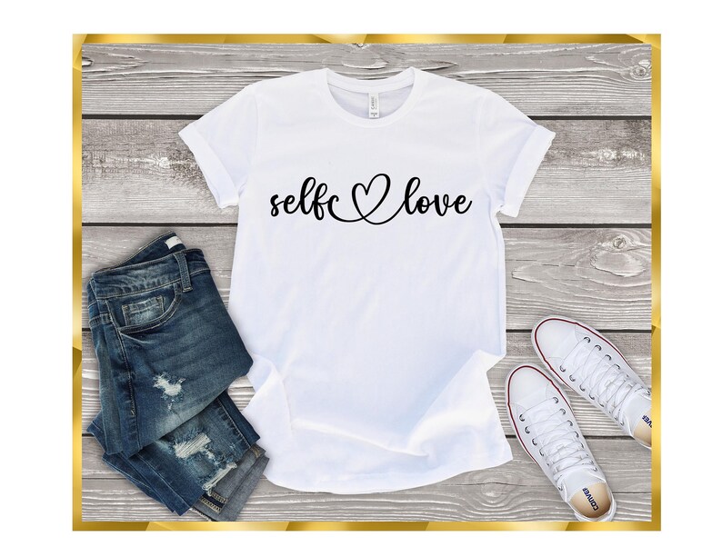 May include: White t-shirt with the text "self love" in black cursive lettering with a heart symbol connecting the words.