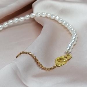 Two-material necklace in stainless steel and genuine freshwater pearls with handcuff pendants