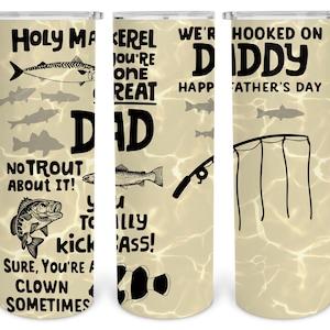 May include: A white tumbler with a fishing theme. It features the text "Holy mackerel you're one great dad", "No trout about it!" and "Sure, you're a clown sometimes". The tumbler also has a fishing rod and fish illustrations.