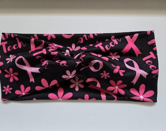 May include: Black headband with a pink ribbon and flower pattern. The headband has the text "Tech" repeated on it.
