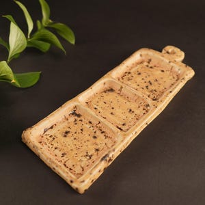 May include: A rectangular ceramic serving dish with three divided sections. The dish is a light beige colour with brown speckles throughout.
