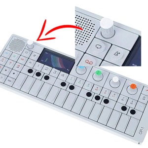 May include: A white synthesizer with a small screen, black keys, and several knobs. The synthesizer has a label that reads "OP-1".