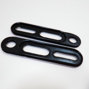 May include: Two black plastic straps with a hole at one end and a slot in the middle.