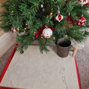 May include: A white, rectangular, marble-like surface with a grey veining pattern. The surface is sitting on a red, folded, cardboard box.