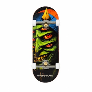 Pode incluir: Um skate de dedo com o gráfico de uma criatura verde de múltiplos olhos usando um gorro azul e laranja. O deck possui eixos de metal prateado com rodas brancas e o texto WOODENBLACK impresso em branco na parte inferior da prancha.