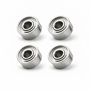 以下が含まれることがあります： 2×2のグリッド状に配置された、4つの同一の銀色の金属製ボールベアリングのセット。各円形コンポーネントは、滑らかで磨かれた外輪と中央の内輪を備えており、クリーンで工業的な金属仕上げが施されています。