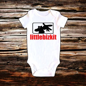 May include: White baby onesie with a black silhouette of a hand and a cartoon animal inside a black square. The text "littlebizkit" is printed in red below the square.