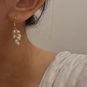 May include: Gold dangle earrings with a cluster of small white pearls.