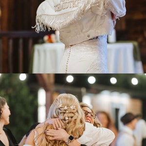 May include: A bride wearing a white wedding dress and a white denim jacket with "Mrs. Schmidtke" embroidered on the back. The bride is hugging another person wearing a black dress.