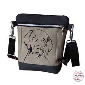 Könnte beinhalten: Eine schwarze und braune Umhängetasche mit einer Reißverschlusstasche und einem schwarzen gestickten Bild eines Hundekopfes auf der Vorderseite. Die Tasche hat einen schwarzen verstellbaren Riemen.