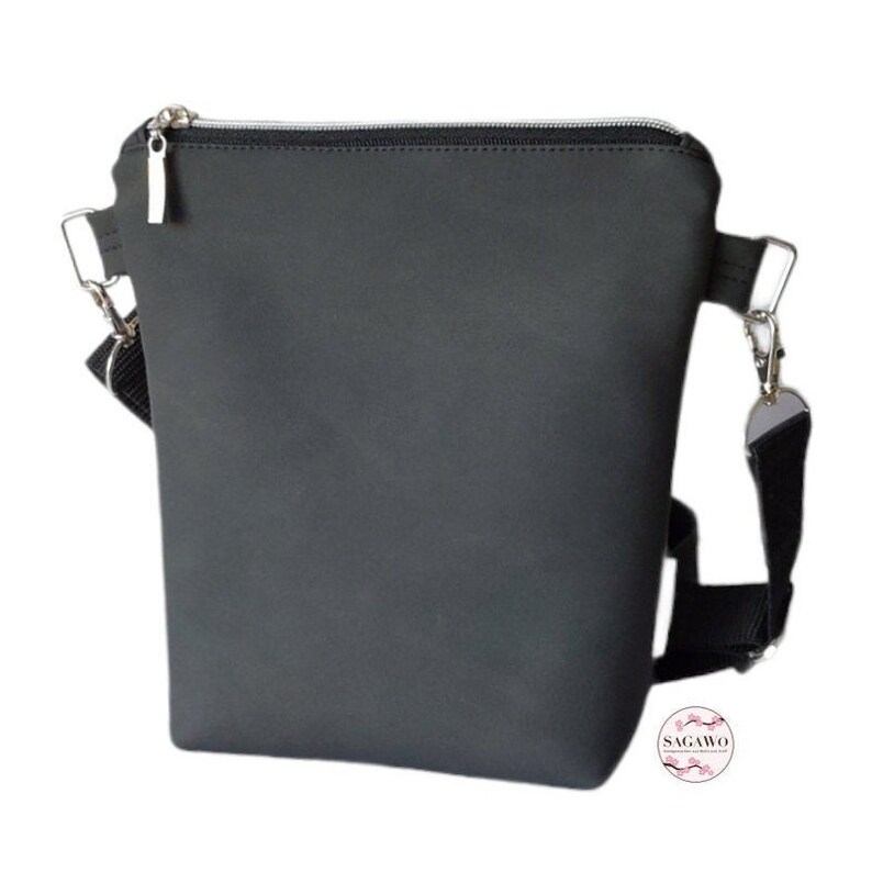 May include: A black crossbody bag with a zipper closure and a silver zipper pull. The bag has a black adjustable strap with a silver clasp.