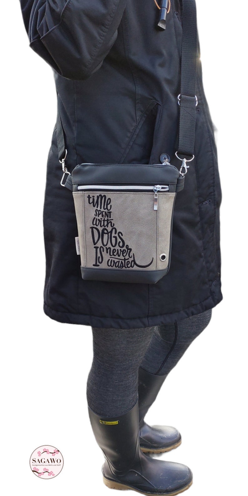 May include: A gray and black crossbody bag with a zipper closure. The bag has a quote embroidered on it that reads "Time spent with dogs is never wasted."