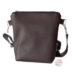 May include: A brown leather crossbody bag with a zipper closure and an adjustable strap. The bag has a silver hardware accent.