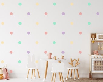May include: A white wall with pastel colored polka dots in shades of mint green, cream, light orchid, and rose peach. The wall is decorated with a play kitchen and a small table and chairs.