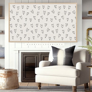 Pu&ograve; includere: Una poltrona bianca con un cuscino a righe bianche e nere si trova di fronte a un camino con una stampa incorniciata di un motivo di cuori bianco e nero. La stampa &egrave; intitolata "HARRIS LANE PRINTS".