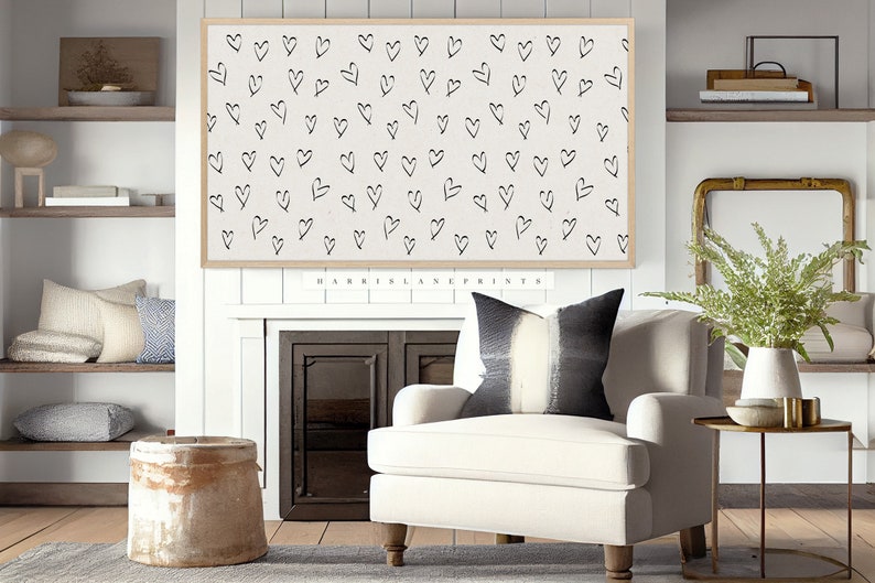 Pu&ograve; includere: Una poltrona bianca con un cuscino a righe bianche e nere si trova di fronte a un camino con una stampa incorniciata di un motivo di cuori bianco e nero. La stampa &egrave; intitolata "HARRIS LANE PRINTS".
