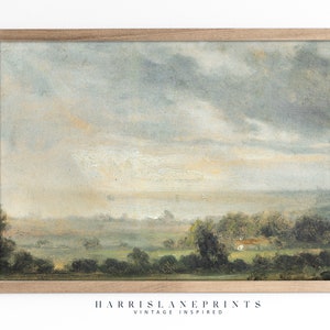 Puede incluir: Una pintura de paisaje vintage en un marco de madera. La pintura representa un cielo brumoso y nublado sobre un campo verde con árboles en primer plano. Los colores son apagados y suaves, con tonos de azul, verde y marrón.