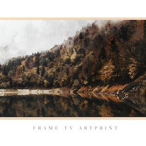 May include: A watercolour painting of a forest reflected in a still lake. The trees are a mix of green, brown, and yellow, and the water is a deep blue. The sky is a soft grey, and there is a light mist in the air.  FRAME TV ARTPRINT