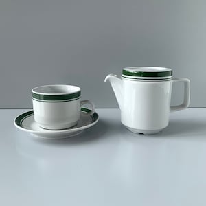 Op de afbeelding: Een wit keramiek theeservies met een groen streepontwerp. De set bevat een theepot, een kopje en een schoteltje.