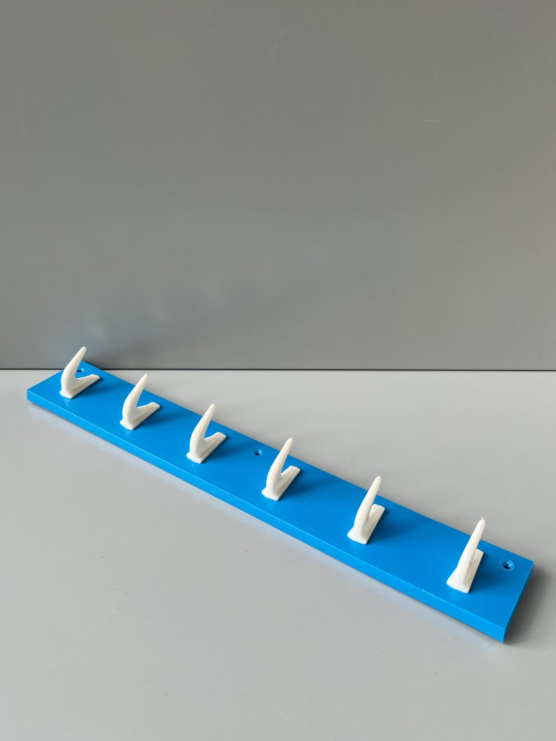 May include: A blue wooden wall-mounted coat rack with six white plastic hooks.