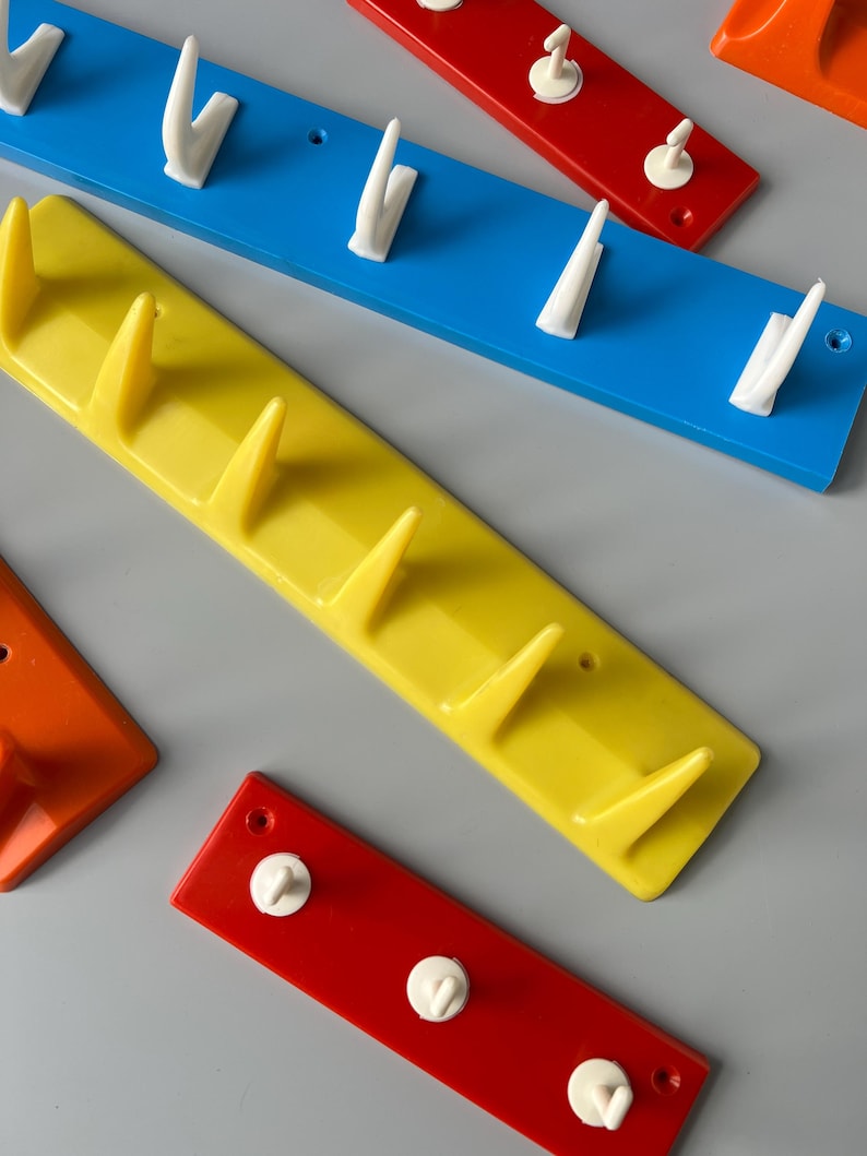 May include: Four wall-mounted hooks in different colours: red, yellow, blue and orange. Each hook has a different number of white plastic hooks.