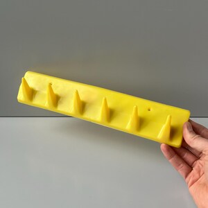 May include: Yellow plastic wall-mounted coat rack with six pointed hooks.