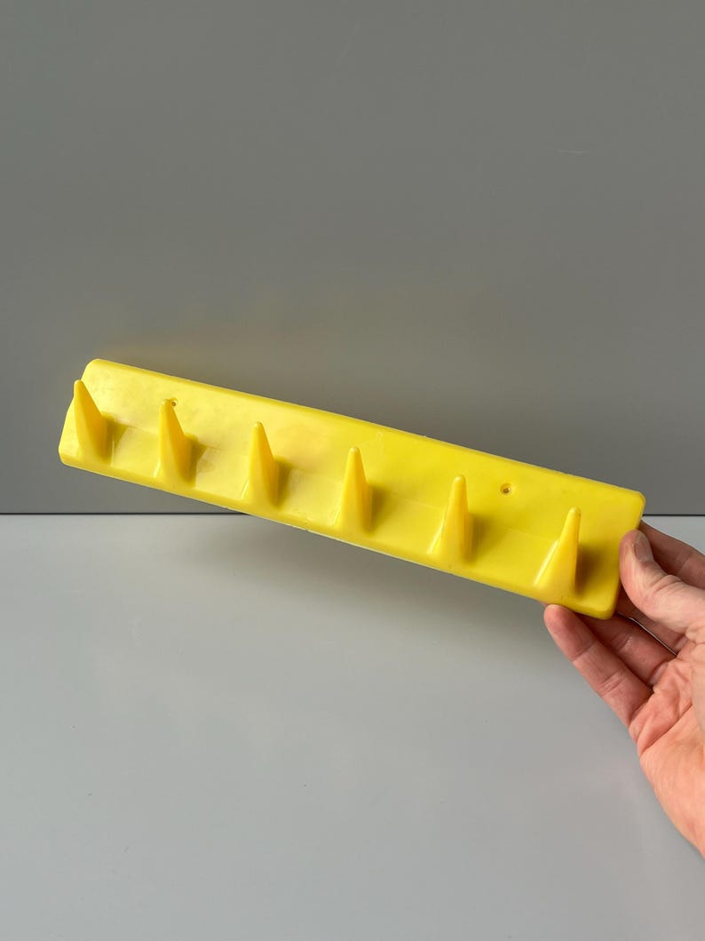 May include: Yellow plastic wall-mounted coat rack with six pointed hooks.