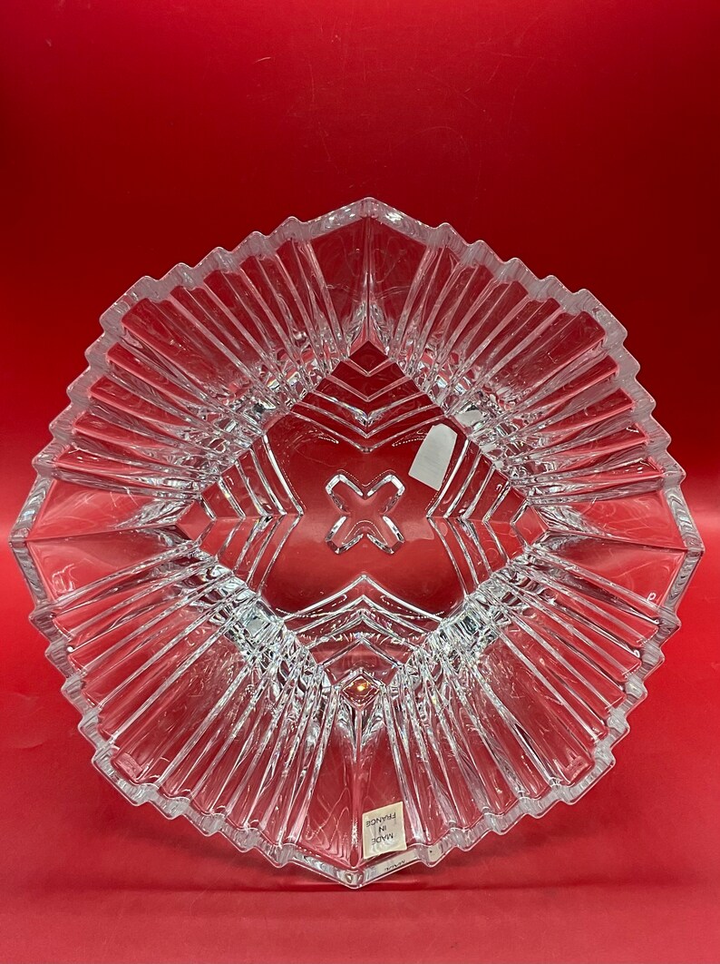 May include: A clear glass bowl with a geometric design. The bowl has a starburst pattern and is made in France.