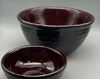 May include: Two brown ceramic bowls, one large and one small, with a glossy finish. The bowls are nested together.