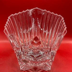 May include: A clear glass bowl with a star-shaped base and a fluted design. The bowl is made of crystal and has a delicate, elegant look.
