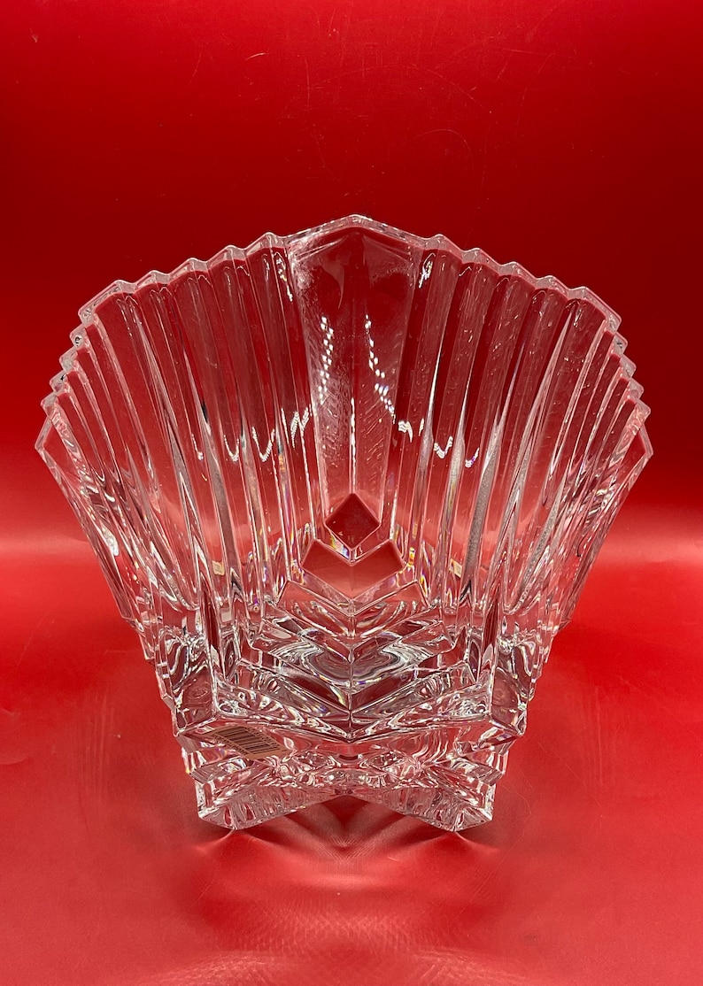 May include: A clear glass bowl with a star-shaped base and a fluted design. The bowl is made of crystal and has a delicate, elegant look.