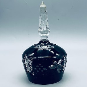 May include: A black crystal bell with a clear crystal knob on top. The bell is decorated with a cut-out design of flowers and grapes.