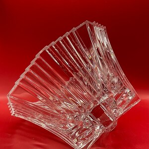 May include: A clear glass bowl with a geometric design. The bowl is made of crystal and has a square shape. The bowl is perfect for serving fruit, snacks, or other treats.