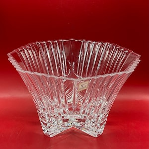May include: A clear glass bowl with a star-shaped base and a fluted design. The bowl has a label that reads "JG Crystal".