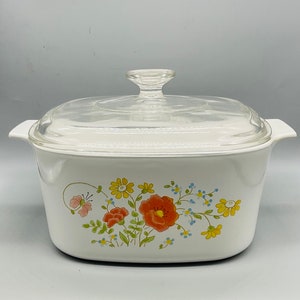 May include: White ceramic casserole dish with a glass lid. The dish features a floral design with red, yellow, and blue flowers.