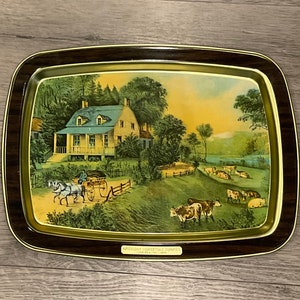 May include: A vintage metal serving tray with a brown wooden frame. The tray features a colorful illustration of a farmhouse with a horse-drawn carriage and cows in a field. The text "Early American Homes" is printed on the bottom of the tray.