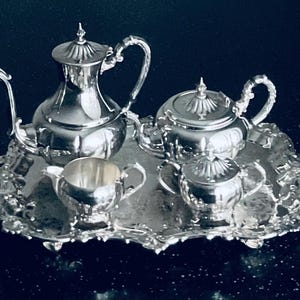 May include: A silver tea set with a teapot, creamer, sugar bowl, and tray. The set is ornate and features a floral design.