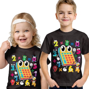 May include: Two children wearing black t-shirts featuring a colourful calculator graphic. The graphic includes numbers, math symbols, and cartoon monster characters. The shirts are short-sleeved and suitable for children.