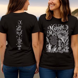 May include: A black t-shirt featuring a white graphic print. The front displays the text "Midnight Margaritas" with illustrations of a margarita, a frog in a hat, a coffee pot, a mushroom, and a crescent moon. The back shows a vertical design.