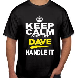 Könnte beinhalten: Schwarzes T-Shirt mit dem Text "KEEP CALM AND LET DAVE HANDLE IT" in Weiß, mit gelbem Unterstrich und Kronen-Grafik. Das Shirt hat einen Rundhalsausschnitt.