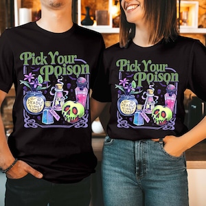 May include: A black t-shirt featuring a graphic print with the text Pick Your Poison. The design includes a blue jar labeled Deadly Night Shade, a pink potion bottle, a blue bottle with a Drink Me tag, and a green skull-shaped apple.