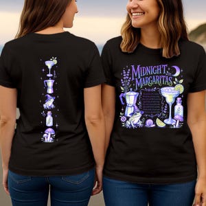 May include: A black t-shirt featuring a graphic print with the text Midnight Margaritas. The design includes a frog wearing a witch hat, a margarita glass, a moka pot, a potion bottle, mushrooms, a snail, and lavender in shades of purple and blue.
