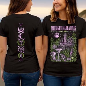 May include: A black t-shirt featuring a graphic print. The front displays a house, a margarita glass, a frog, and a coffee pot with the text "MIDNIGHT MARGARITAS EST. 1998". The back features a vertical column of symbols including a frog, moon, and glass.
